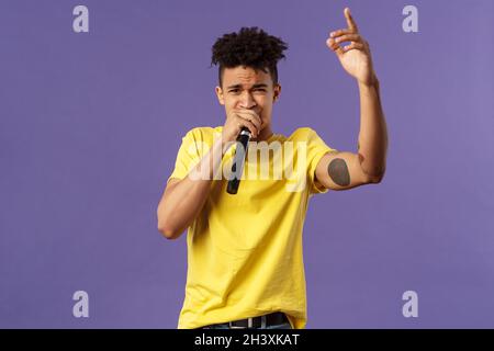 Porträt eines jungen sorglosen, frechen Hipster-Typen mit Tattoos, gelbes T-Shirt, das vor Publikum mit seinem Hip-Hop oder Rap auftrat, Stockfoto