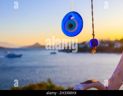 Blau böse Auge Amulett auf dem Hintergrund einer wunderschönen Seenlandschaft bei Sonnenuntergang Stockfoto