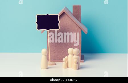 Hölzerne Familienfiguren, Modellhaus. Immobilienkauf, Mietkonzept. Umzug in neue Wohnungen Stockfoto