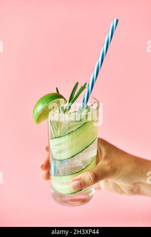Junge Frau Hand hält kalten Cocktail in Glas auf rosa Hintergrund Stockfoto