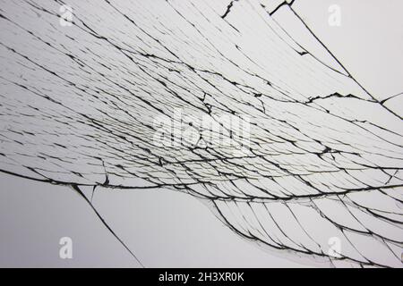 Zerbrochenes Glas im Fenster auf hellgrauem Hintergrund. Cracks Konzept für Design. Stockfoto