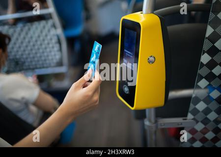 Asiatische Frau, die ohne Kontaktlosigkeit mit Plastikkarte für den öffentlichen Verkehr im Bus bezahlt Stockfoto