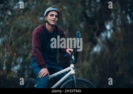 Professioneller junger Sportler Radfahrer mit bmx Fahrrad im Skatepark. Stockfoto