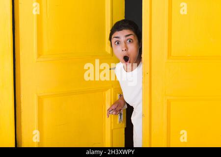 Junge inderin guckt durch die gelbe Tür. Stockfoto