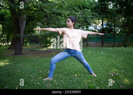 Indische Frau, die im Sommerpark im Freien Yoga macht Stockfoto