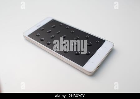 Mobiltelefon mit Tropfen auf oleophoben Bildschirm. Stockfoto