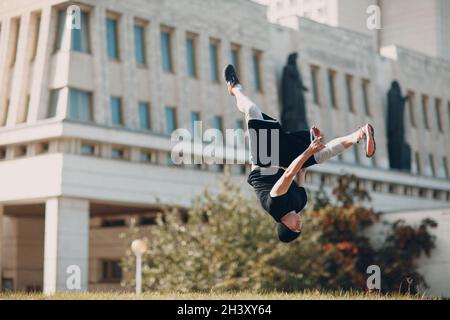 Junger sportlicher Kerl, der Parkour an der Stadtstraße macht. Stockfoto