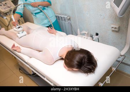 Junge schöne Frau und LPG-Massageverfahren in der Kurklinik. Lymphatische Entwässerungsmassage Flüssiggas-Apparat-Prozess. Stockfoto