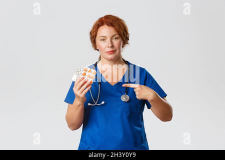 Medizin, Gesundheitswesen und Coronavirus-Konzept. Selbstbewusste professionelle medizinische Mitarbeiterin, weibliche Ärztin in Scrubs verschreiben Behandlung Stockfoto