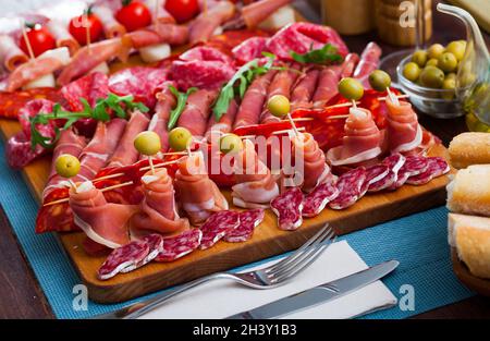 Spanische leckere Mahlzeit Schneiden von Würstchen und Schinken mit Kirschtomaten und Oliven Stockfoto