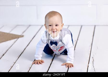 In der Lounge kriecht ein fröhliches weißes Kleinkind auf dem Boden. Stockfoto