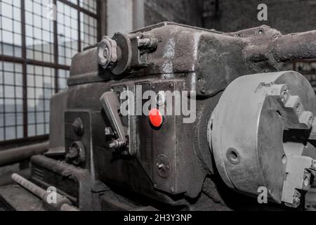 Roter Startknopf zur Steuerung der alten Fräsmaschinen-Ausrüstung in der Werkstatt im Industriewerk. Stockfoto