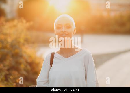 Millenial junge Frau blond kurze Haare im Freien lächelnd Porträt. Stockfoto