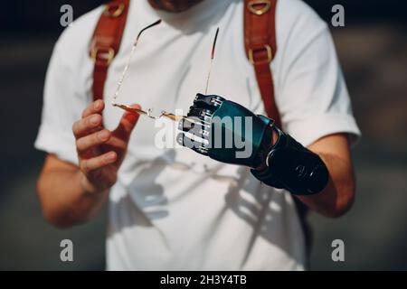 Junge behinderte Mann Porträt auf gelbe Gläser mit künstlichen prothetischen Hand gesetzt. Stockfoto