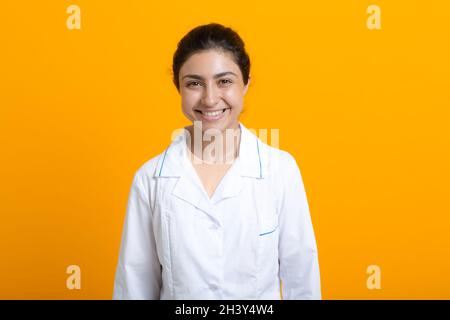 Porträt der indischen Ärztin in weißem medizinischen Kleid isoliert auf gelbem Hintergrund Stockfoto