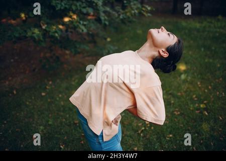 Sportliche Millennial Indian Woman in Freizeitkleidung Stretching vor dem Training im Park, Aufwärmübungen Stockfoto