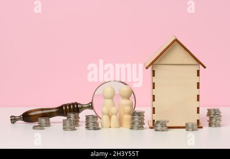 Holzfiguren einer Familie, Stapel von Metallgeld, ein Miniatur-Holzhaus. Immobilienkauf, Hypothekenkonzept. Akkumulat Stockfoto