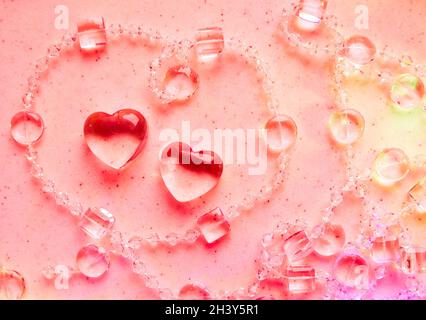 Transparente Herzen und Perlen auf Marmor in rosa Ton. Perfekte Valentinstag Grußkarte Hintergrund. Stockfoto