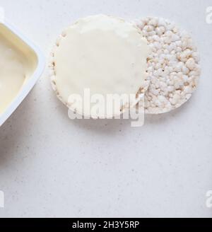 Gesunde organische Reiskuchen mit Frischkäse auf weißem Marmor. Stockfoto