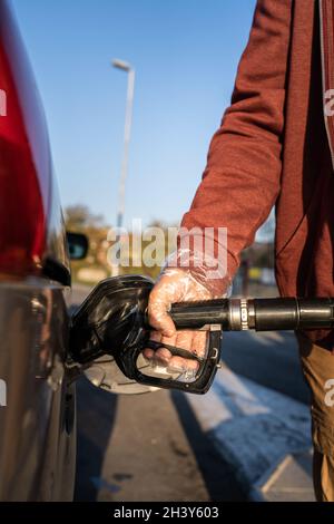 Nahaufnahme auf der Hand von unbekannten kaukasischen Mann halten schwarze Gaspumpe Düse Benzin in den Kraftstofftank tanken Benzin zum Fahrzeug auf Selbstbedienung Stockfoto