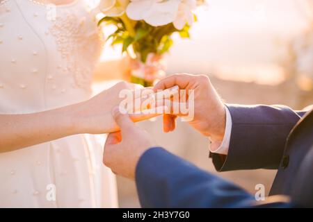 Der Bräutigam legt den Ring während der Hochzeit auf den Finger der Braut Die Hochzeitszeremonie Stockfoto