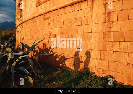 Silhouetten eines Mannes und einer Frau an der orangefarbenen Wand eines alten Gebäudes an einem sonnigen Tag. Stockfoto