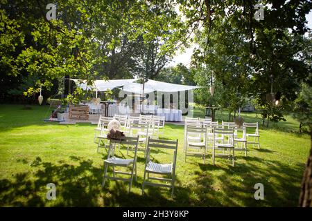 Hochzeitsstühle, in Reihen im Park, mit handgefertigten Dekorationen Stockfoto