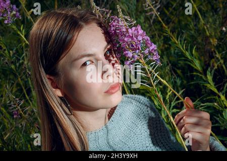 Hübsche junge Frau im Freien im Park mit Sommerblumen Stockfoto