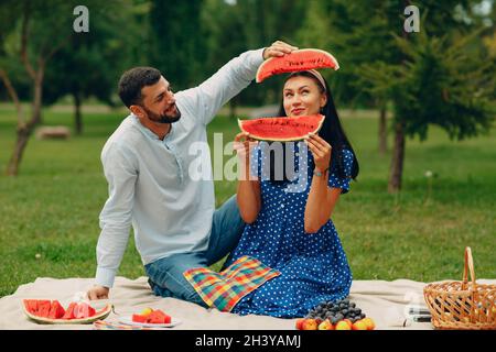 Junge Erwachsene Frau und Mann Paar Picknick auf grünem Gras Wiese im Park Spaß mit Wassermelone Stockfoto