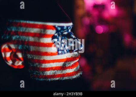 Erwachsener Mann mit USA-Flagge im Gesicht im Dunkeln. Stockfoto