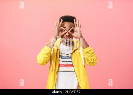 Der Typ, der beeindruckt ist, kann es nicht glauben, dass seine eigenen Augen durch Kreise ziehen, die aus Fingern an der Kamera gemacht wurden, aufgeregt und erstaunt darüber stehen Stockfoto