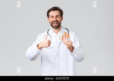 Krankenhaus, medizinisches Personal, covid-19 Behandlungskonzept. Glücklich fröhlich kaukasischen Arzt lächelt, zeigen Daumen-up in Zustimmung und Stockfoto