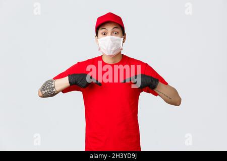 Überrascht keuchenden asiatischen Entbindung Mann in roter Kappe und T-Shirt, trägt Schutzmaske und medizinische Handschuhe, um die Ausbreitung des Virus zu verhindern, Stockfoto