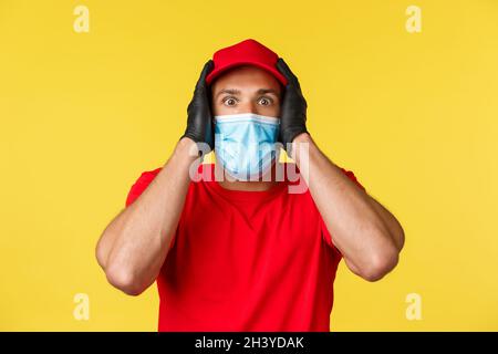 Covid-19, Lieferaufträge, Shopping, kontaktloses Bezahlen und soziales Distanzierungskonzept. Schockiert und beeindruckt Kurier in roten Uni Stockfoto