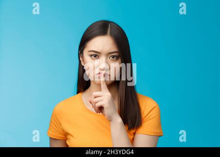 Hush Bleib still. Seriös aussehende asiatische Mädchen unzufrieden mürrisch zeigen Shush Zeichen drücken Zeigefinger Lippen, runzelig aufgeregt, tel Stockfoto