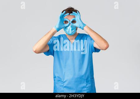 Coronavirus-Ausbruch, medizinisches Personal im Kampf gegen Krankheiten, Krankenhauskonzept. Lustige männliche Arzt in Scrubs und medizinische Maske, glov Stockfoto