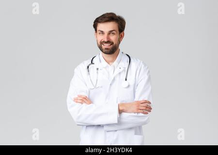 Krankenhaus, medizinisches Personal, covid-19 Behandlungskonzept. Erfolgreicher professioneller Arzt in weißen Scrubs mit Stethoskop, Kreuz Stockfoto
