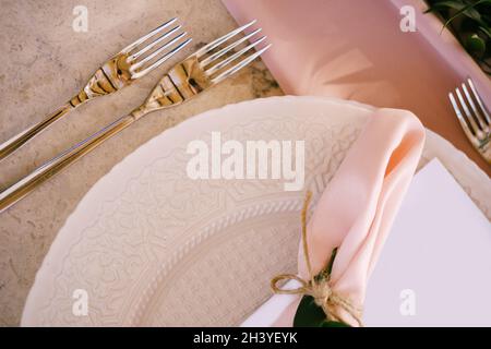 Hochzeitsessen Tischempfang. Steintisch mit rosa Läufer, Teller mit Muster und rosafarbene Servietten, Kerzen mit LED-Licht b Stockfoto