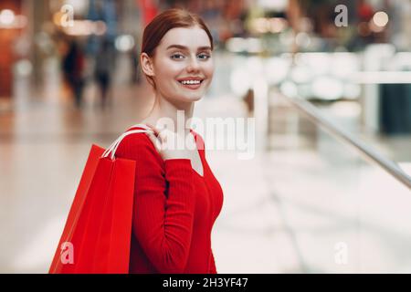 Junge Frau mit roten Papiertüten im Einkaufszentrum. Black friday und Valentines Day Konzept Stockfoto