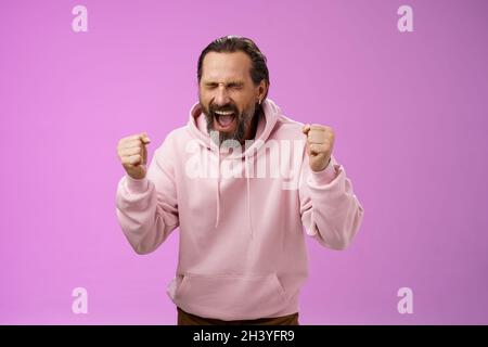 Vollendete glücklich fröhlich triumphierend reifen 40er bärtigen Mann grauen Haaren brüllend ja begeistert freudig klatschende Fäuste feiern suc Stockfoto