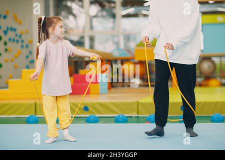 Kinder machen Übungen mit Springseil im Fitnessstudio im Kindergarten oder in der Grundschule. Sport- und Fitnesskonzept für Kinder. Stockfoto