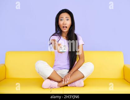 Aufgeregt überrascht Frau Fernsehen ändern Sender mit einer Fernbedienung Stockfoto