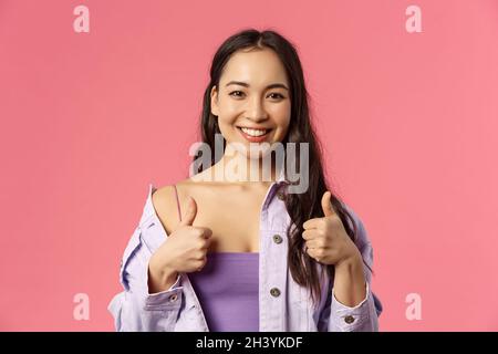 Klingt gut im in. Close-up Porträt von zufrieden, aufgeregt lächelnd schöne asiatische Mädchen in stilvollem Outfit, empfehlen Produkt, pl Stockfoto