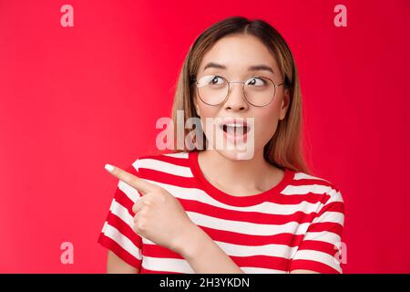 Amüsiert gewundert süß asiatisch blond modern girl überrascht, suchen zeigen links intrerested offenen Mund fasziniert erstaunt, Überprüfung Stockfoto