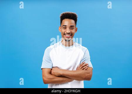 Porträt eines selbstbewussten ehrgeizigen afroamerikanischen freundlichen Mannes mit Bart und Afro-Haarschnitt, der die Hände auf Brust und smi gekreuzt hält Stockfoto