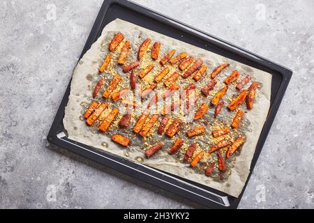 Süßkartoffel mit Käse auf Backblech auf grauem Hintergrund Stockfoto