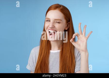 Freche attraktive rothaarige Mädchen winken geheimnisvoll lächeln breit geben Genehmigung Zeichen zeigen okay ok ausgezeichnete Geste zufrieden g Stockfoto