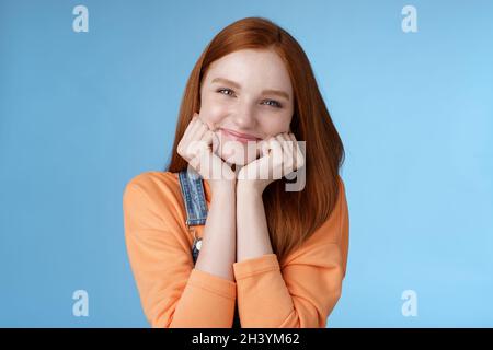 Zärtlichkeit, Wohlbefinden, Schönheitsgefühl. Attraktive junge Ingwer Mädchen reine Haut blaue Augen schlanke Handflächen dumm lächelnd Kamera aussehen amus Stockfoto