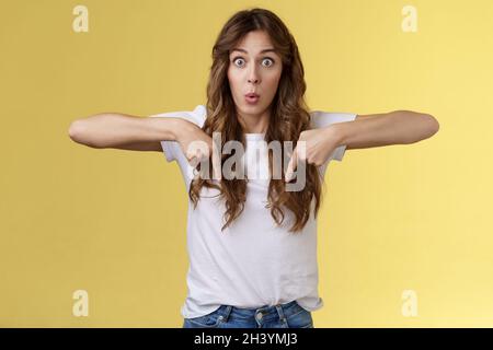 Das sehen Sie auch. Überrascht verwundert erstaunt glücklich erstaunt lustig fröhlich Mädchen lange lockige Frisur starren beeindruckt erstaunt Punkt Stockfoto