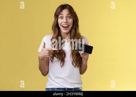 Fröhlich überrascht niedlichen glücklichen Mädchen schlagen beste Ergebnis awesome Spiel zeigt Smartphone-Display zeigt Zeigefinger horizontalen Scre Stockfoto